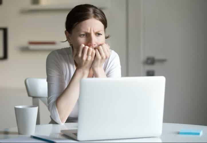 Woman looking most concernedly at a laptop in her home