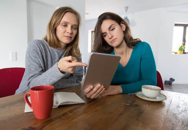 Two women looking confused while reading something on their ipad