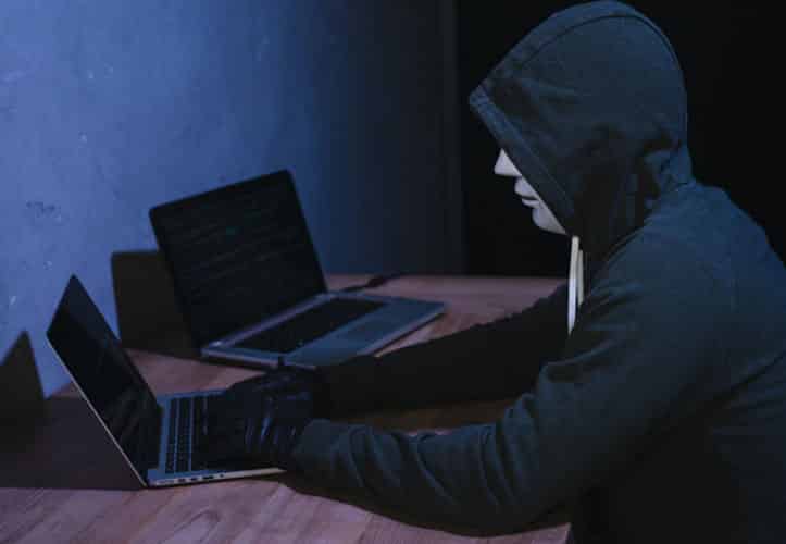 Suspicious person trying to hack an organisation in a dark, dirty room